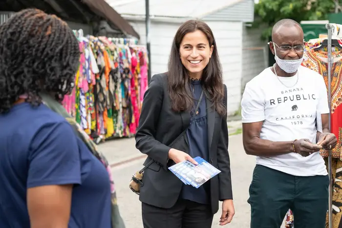 Tali Farhadian Weinstein smiles while campaigning; two people are next to her